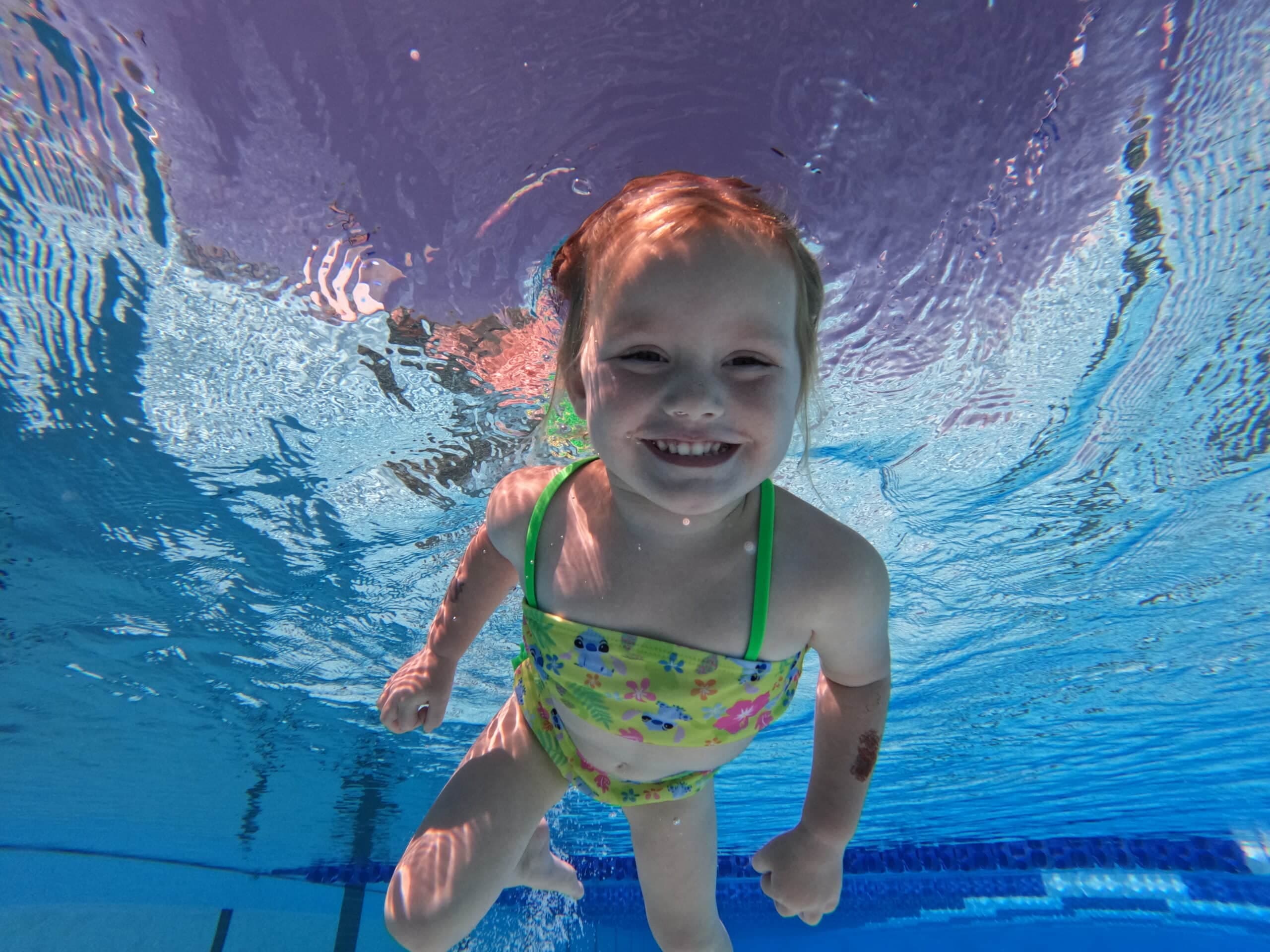 Young girl swimming underwater with a joyful smile during ISR swim lesson